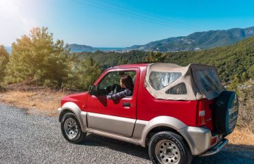 A red SUV driving through the mountainous landscape of Alanya, Turkey on a sunny day.